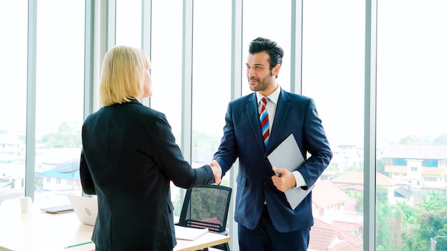 Mand and woman shacking hands in a office building.